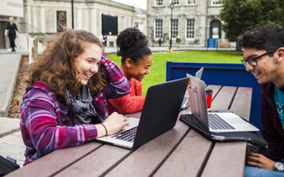 Studenti universitari sorridenti con computer portatili sul tavolo del campus
