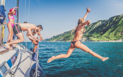 Wieloetniczna grupa przyjaciół żeglujących na łodzi - Letnie wakacje, młodzi dorośli dobrze się bawią