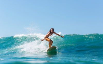 Piękna młoda brunetka w bikini w stroju kąpielowym na fali. Sportowa surferka surfująca na Mauritiusie na Oceanie Indyjskim na tle błękitnego nieba, chmur i przezroczystych fal. Outdoor Aktywny.